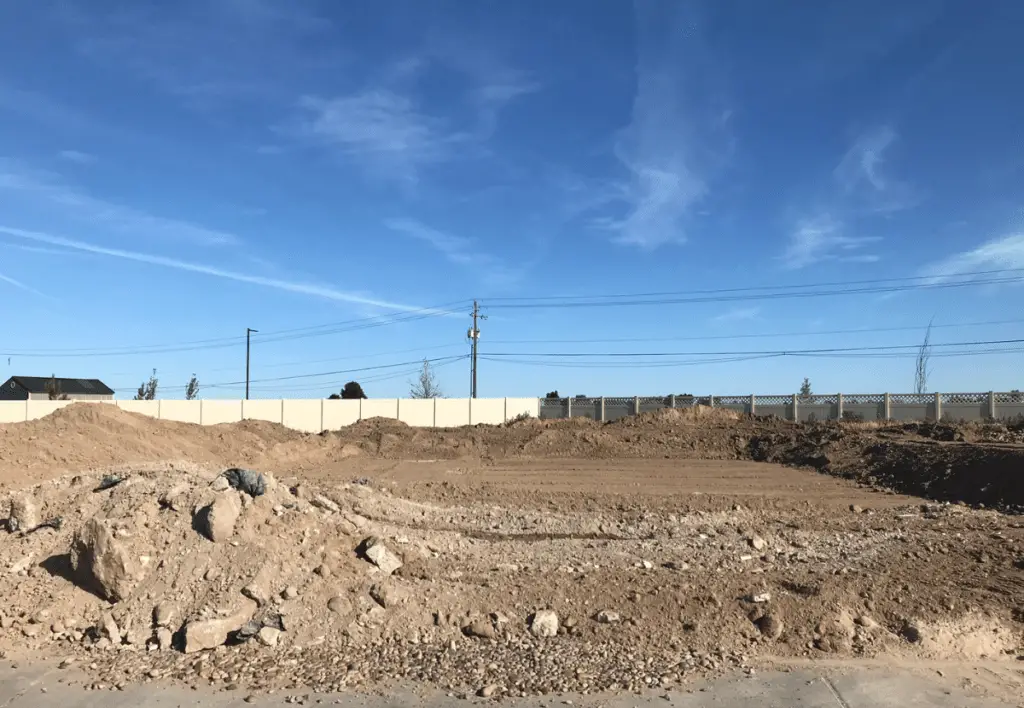 An empty lot full of dirt where a house is being built.