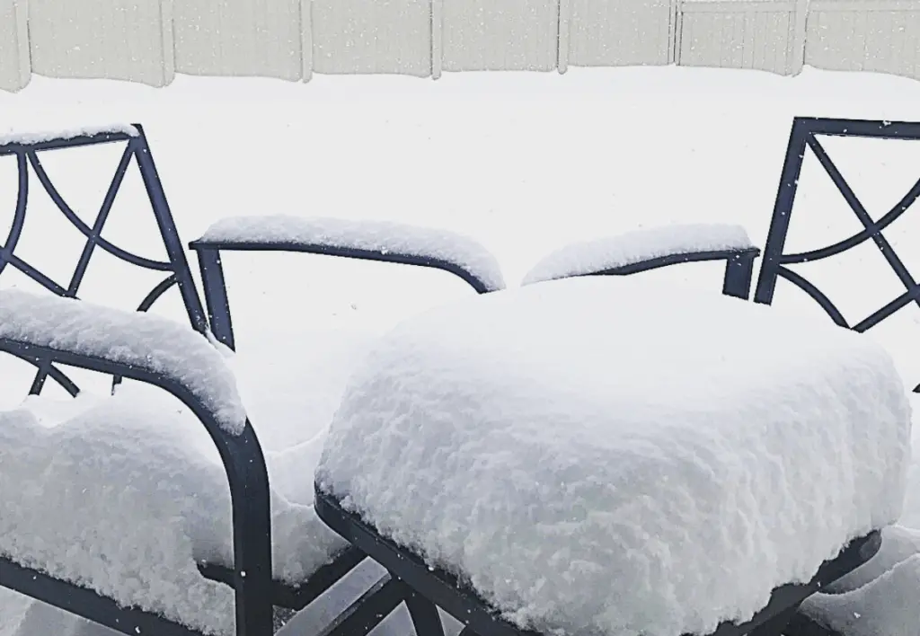 Snow falling on a patio set.